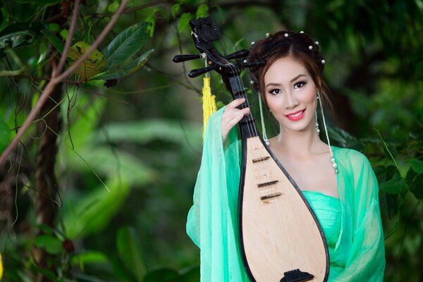 Asian girl in green plays a musical instrument