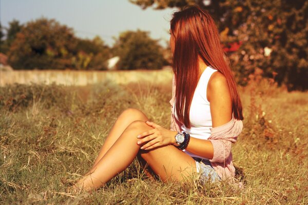 Chica sentada en la hierba en medio del campo