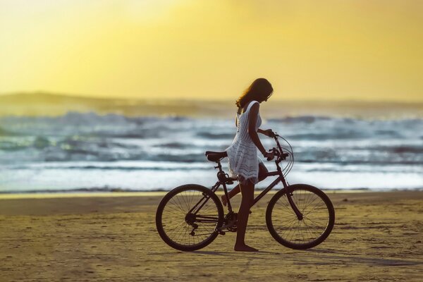 A girl on a bicycle rides on the beach