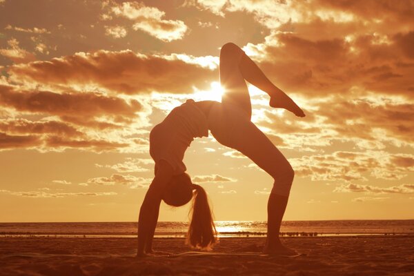 A gymnast girl is engaged on the beach