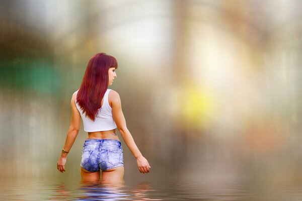 A girl in short shorts and a white T-shirt tables in the water