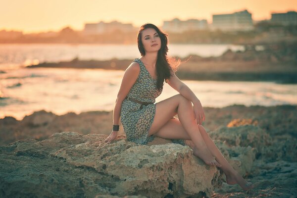 A girl sitting on a rock on the shore