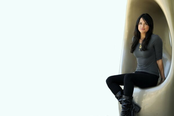 Michelle Rodriguez est assise en jeans et bottes sur une chaise