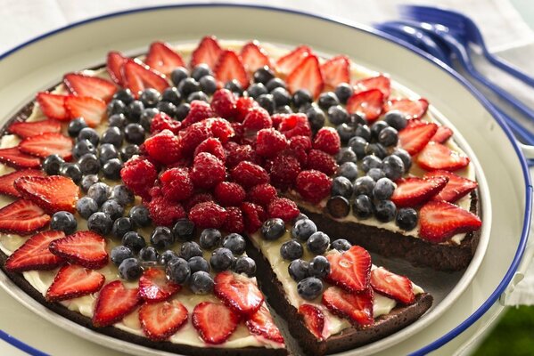 Kuchen auf einem Teller mit Heidelbeeren, Erdbeeren und Himbeeren