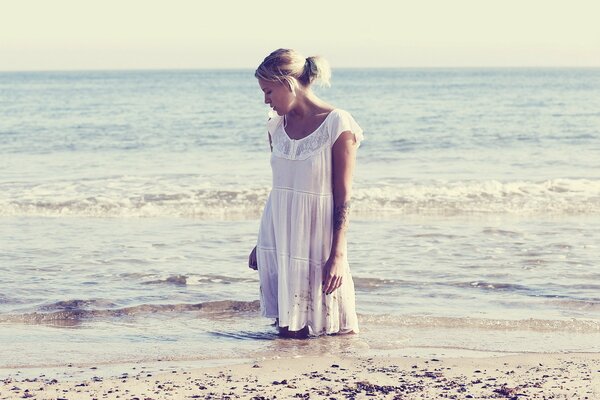 Fille en robe blanche posant sur fond de vagues de la mer