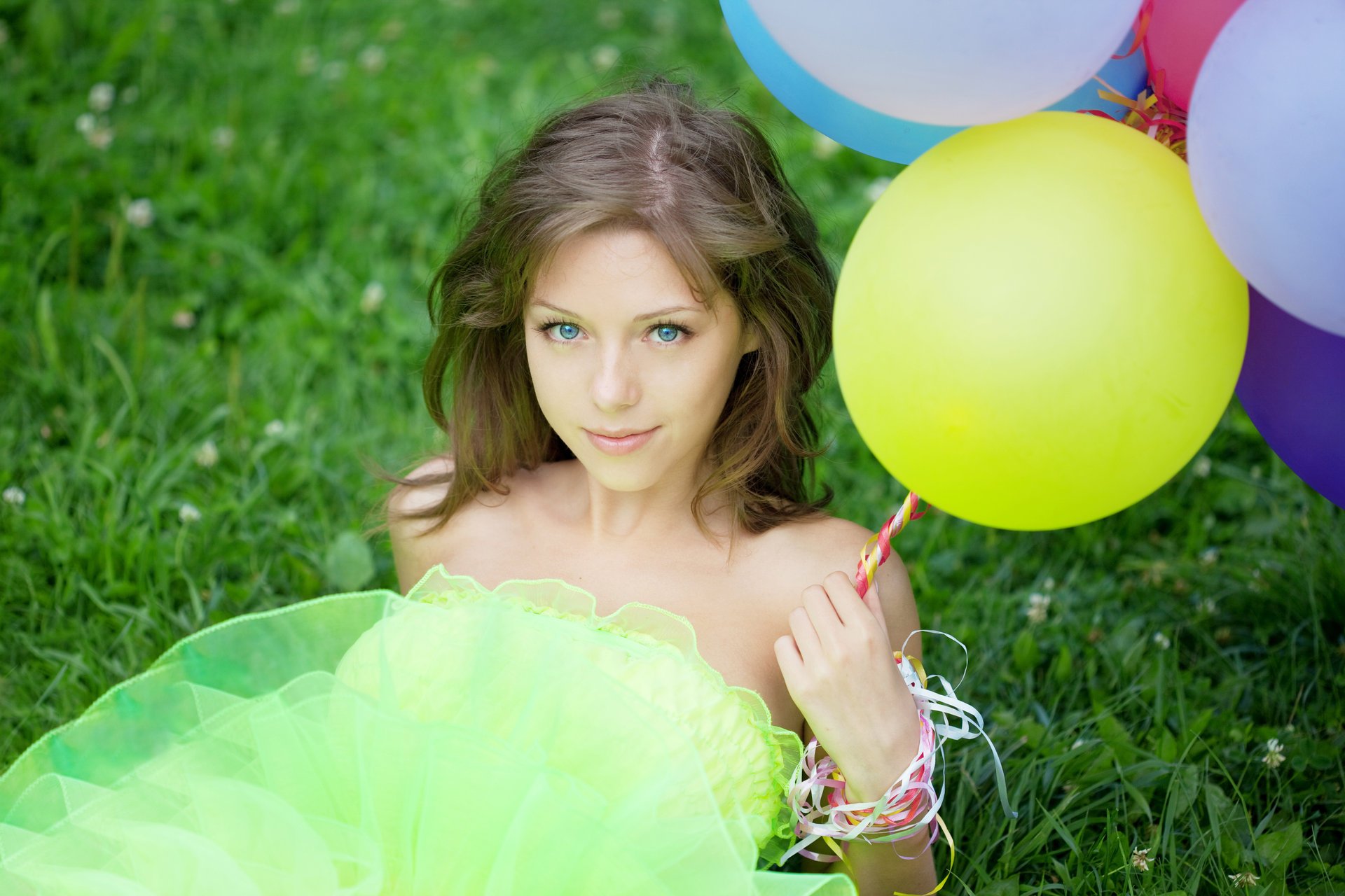 fille aux yeux bleus brune ballons herbe trèfle regard. sourire boucles