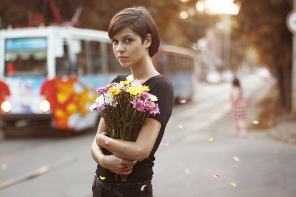 Fille aux yeux bruns avec des fleurs au milieu d une ville animée