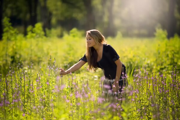 Mädchen berührt die Blumen im Feld