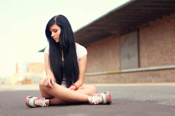 Brunette in the lotus position on the asphalt