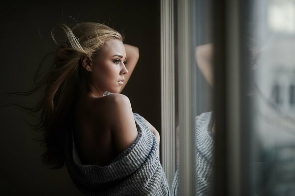 A girl with blonde hair looks out the window