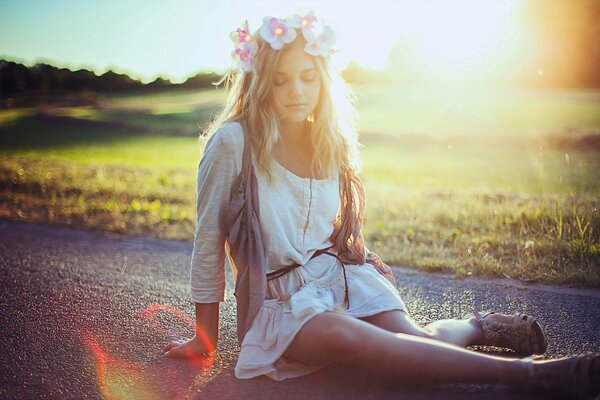 Jeune fille assise sur la route sur fond de soleil