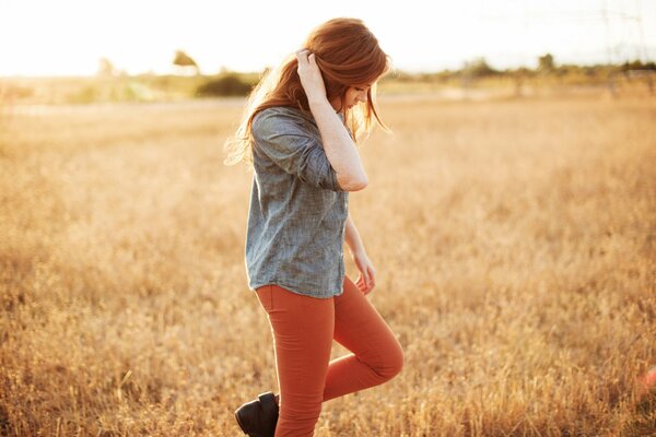 Red-haired girl in the field, in the grass