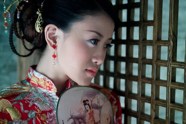 Beautiful Chinese woman in national dress and with a fan