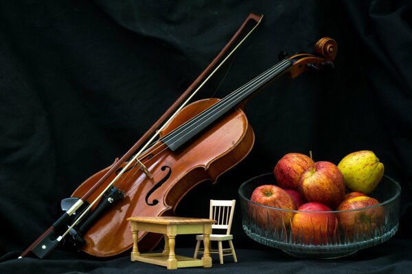 Violine, Äpfel, Tisch mit Stuhl auf schwarzem Hintergrund