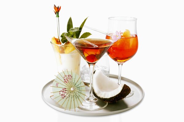 Cocktails in glasses with an umbrella on a tray with coconut