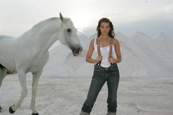 Biały koń i Yvonne Catterfeld na piasku na tle gór