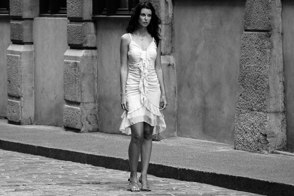 Morena con vestido blanco y zapatos caminando sobre Azulejos en la ciudad