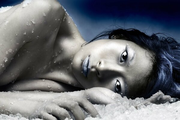 The girl is lying on the ice with a frozen look