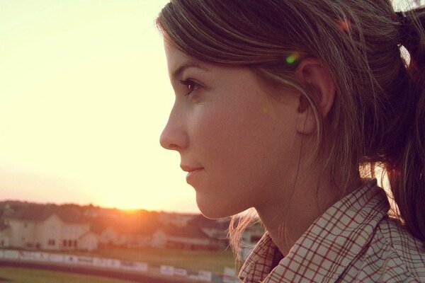 Profil de la jeune fille sur fond de coucher de soleil