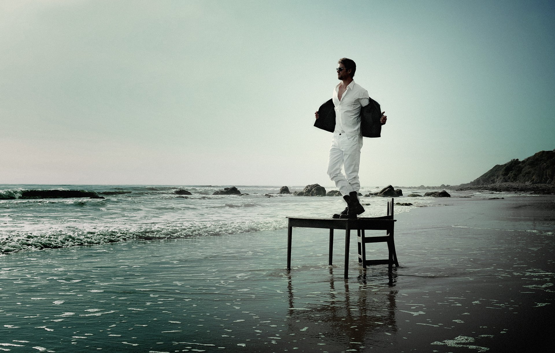 chris hemsworth acteur debout en blanc costume sur la table lunettes bottes plage mer côte pierres sable photographe yu cai magazine flaunt