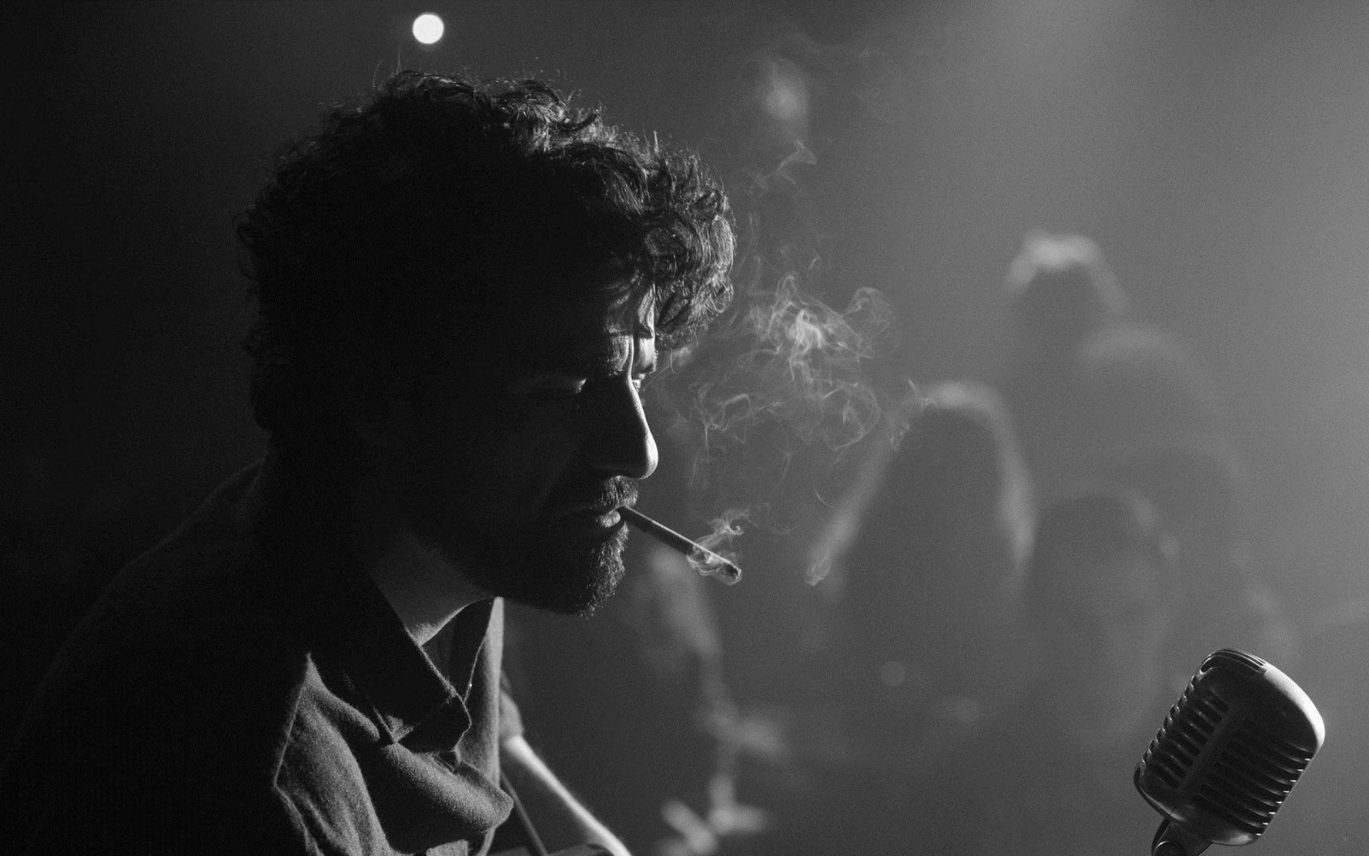 dentro de lewis davis oscar isaac hernández oscar isaac actor b / w blanco y negro penumbra micrófono cigarrillo humo audiencia público rizos rizos barba