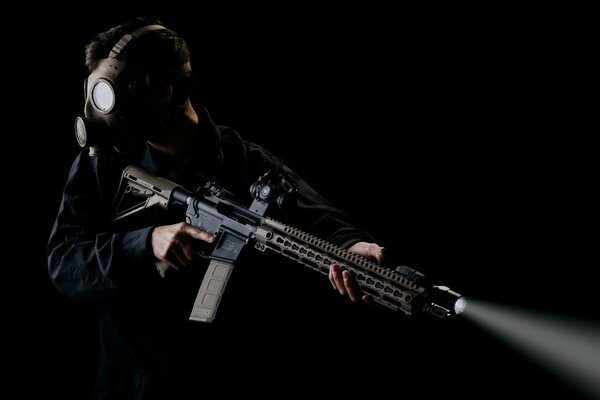 Soldier with a gun in a gas mask on a black background