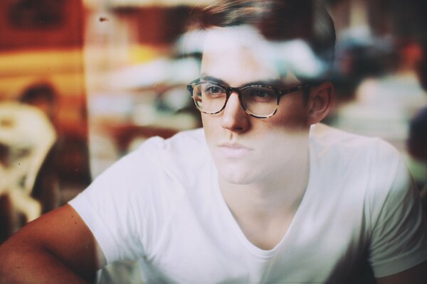 A young man with glasses and a white T-shirt