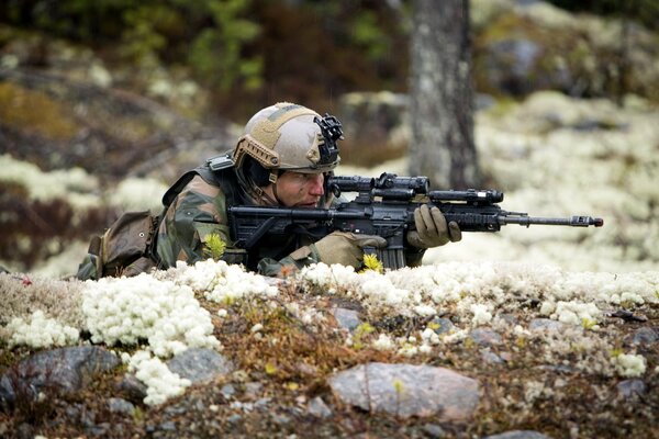 Ein Soldat liegt mit einer Waffe in einem Hinterhalt