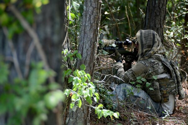 A disguised soldier with a gun in the forest