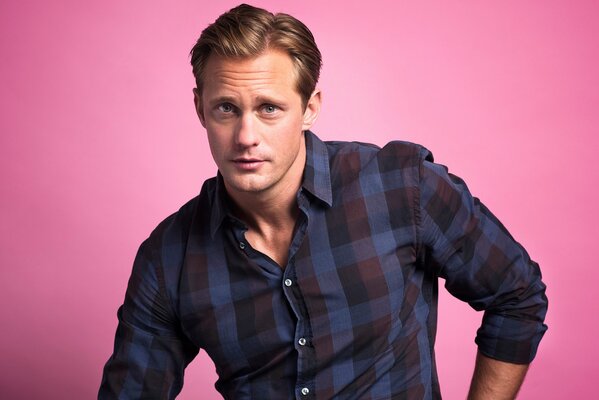 Alexander Skarsgard en una camisa sobre un fondo rosa