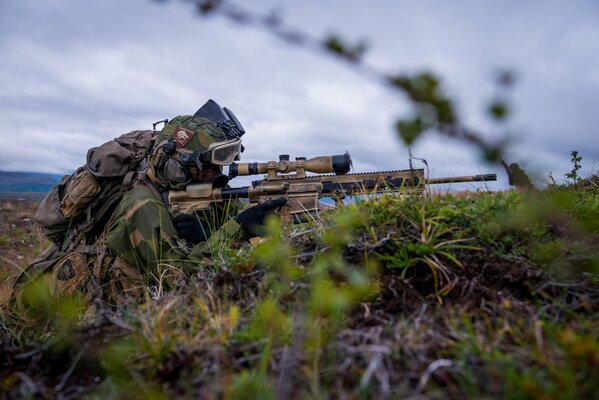 Ein Scharfschütze, der im Graben sitzt, hält das Gewehr bereit