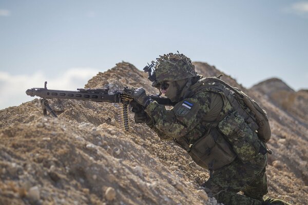 Estnischer Soldat mit einer Waffe in einem Hinterhalt auf einem Felsen