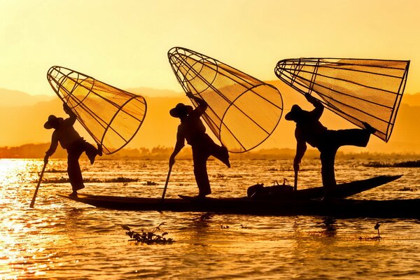 Silhouetten von Fischern am Fluss bei Sonnenaufgang