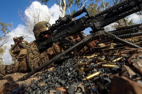 A soldier lying down aims a machine gun