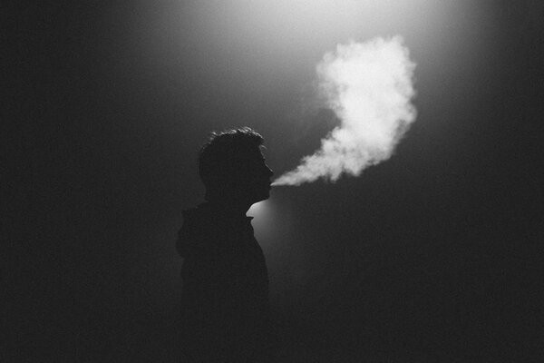 The silhouette of a man. exhaling smoke