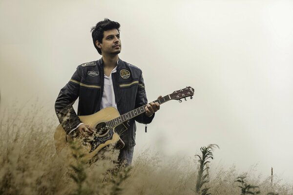 The guitarist plays in nature in the field