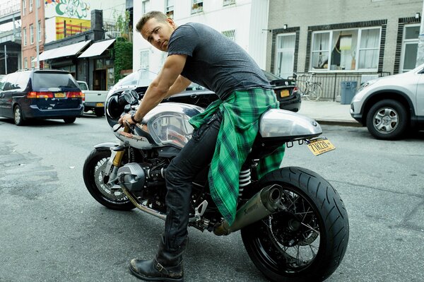 Un gars dans un t-shirt gris est assis sur une moto