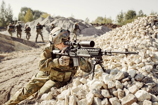 Soldat regardant dans la vue télescopique couché sur les rochers