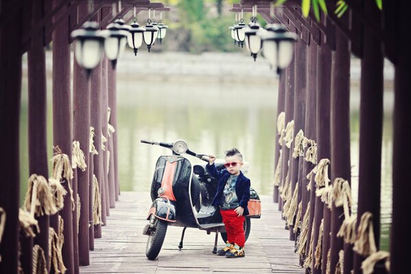 Junge mit Motorroller auf dem Hintergrund des Flusses