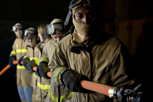 Cinque vigili del fuoco che tengono il tubo