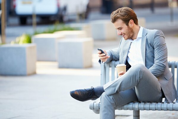 Hombre de negocios Lee un mensaje en su Teléfono y sonríe