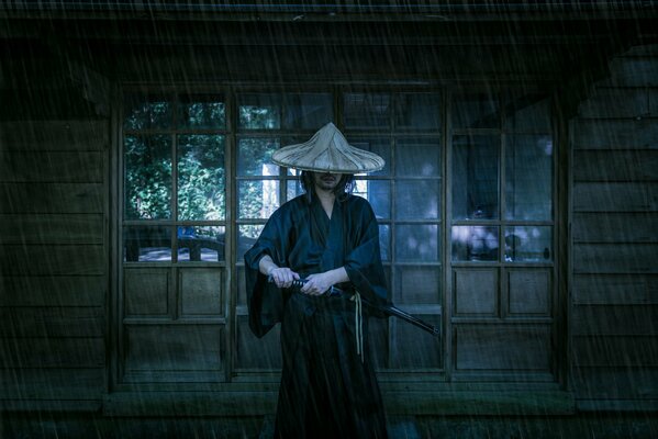 A samurai holds a katana in the rain