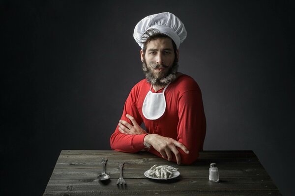 Homme assis à une table en bois, en costume de cuisinier