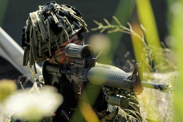 A soldier looks through the optical sight of a rifle