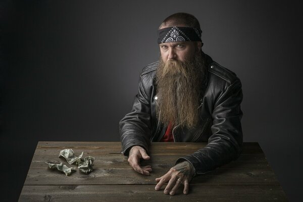 A bearded biker is sitting at a wooden table