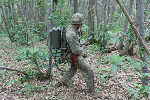 Hombre en komuflage, en el bosque con un lanzallamas