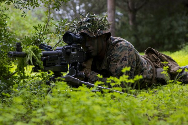 Maskierung eines Soldaten mit einem Maschinengewehr im Gras