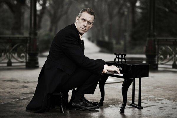 Hugh Laurie we fraku gra na fortepianie w parku