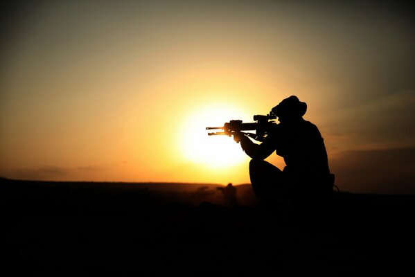 Silueta de un soldado con una ametralladora al atardecer