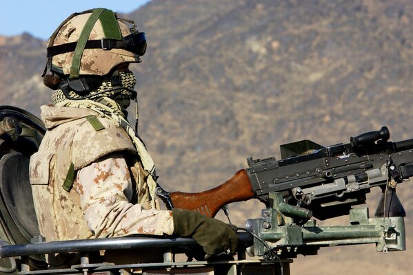 A man in equipment shoots a machine gun